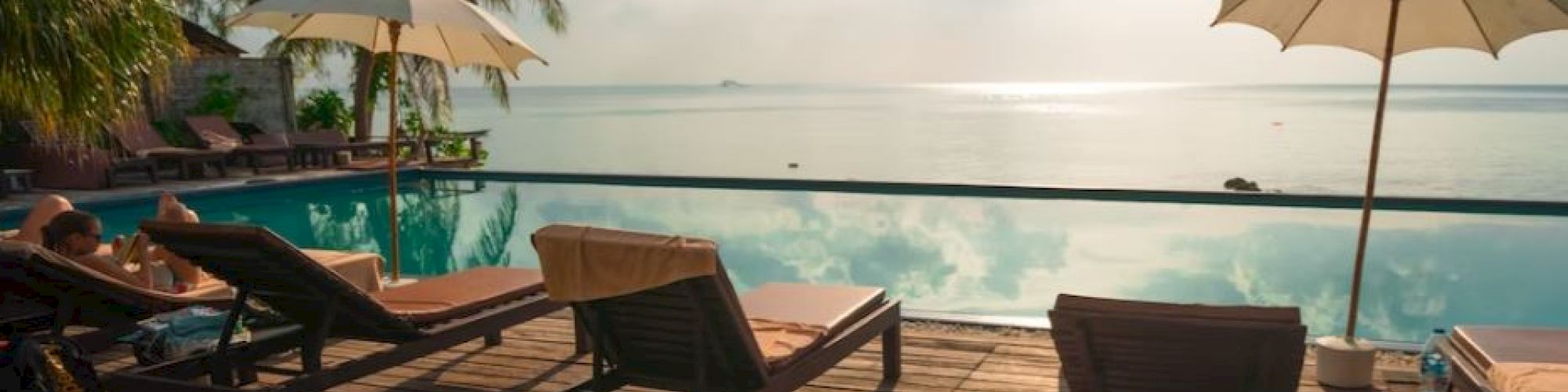 A serene beachside scene with lounge chairs, umbrellas, and a calm ocean under a partly cloudy sky, perfect for relaxation.