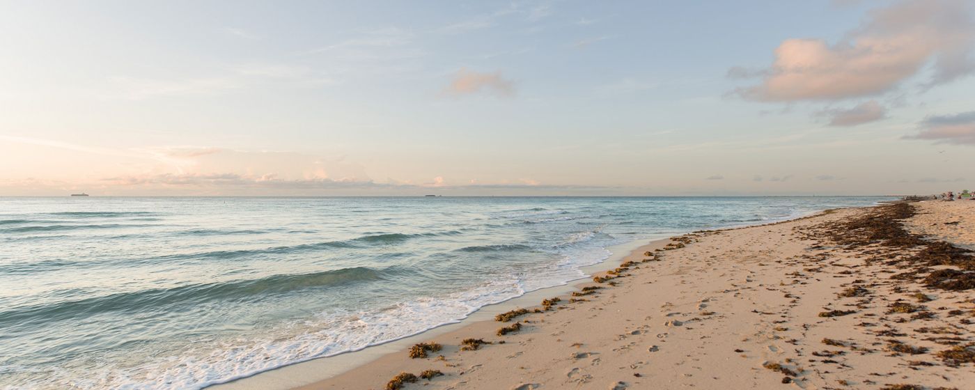 A serene beach scene with waves gently lapping at the shore under a partly cloudy sky.