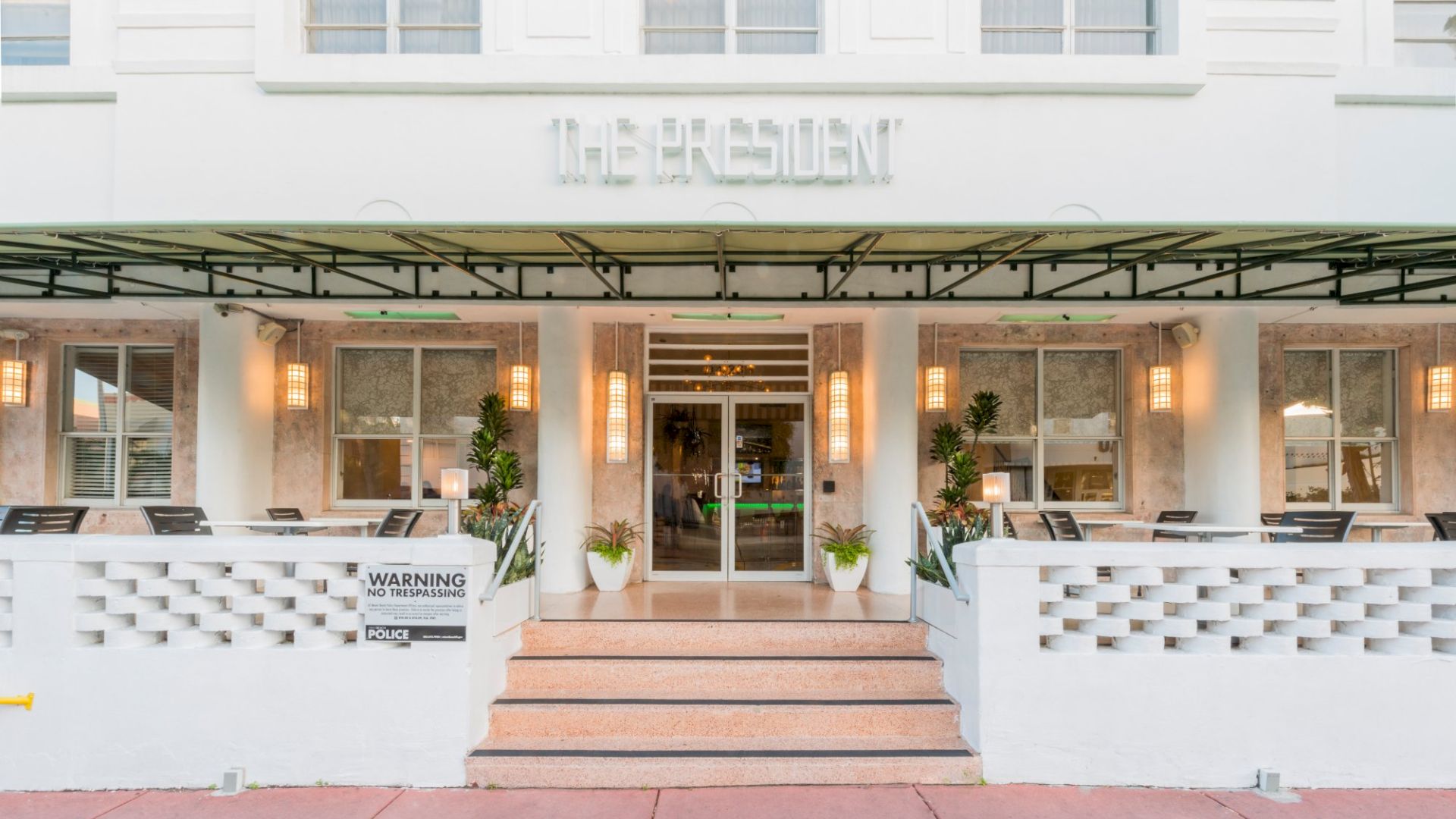 The image shows the entrance of a building with the sign "The President" above the door, featuring steps, potted plants, and a canopy.