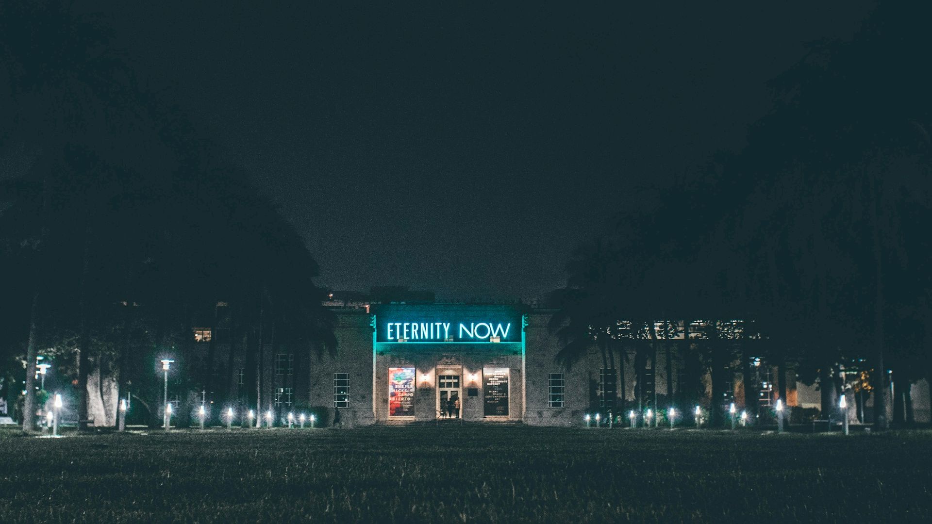 The image shows a building at night with the bright sign "ETERNITY NOW" above the entrance, surrounded by trees and illuminated pathways.
