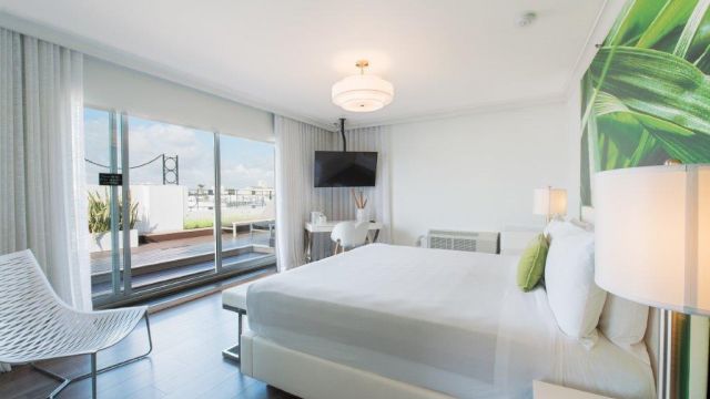 A bright and clean hotel room with a large bed, window, and TV