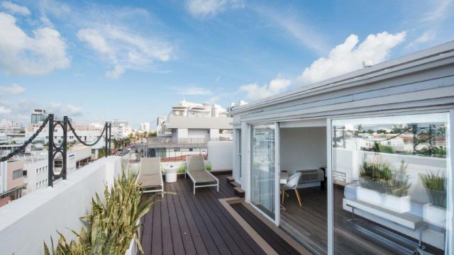 A rooftop deck with lounge chairs and plants overlooking the city skyline