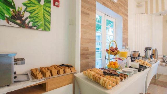 A breakfast buffet with pastries and beverages in a brightly lit room with a window.
