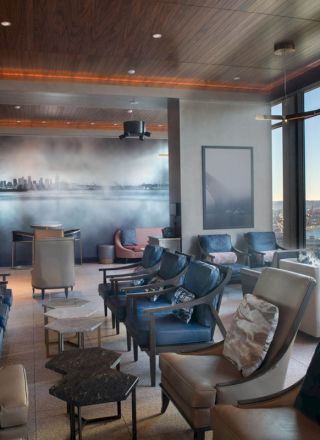 A lounge area with various seating arrangements, a city skyline mural, large windows with an outside view, and modern decor.
